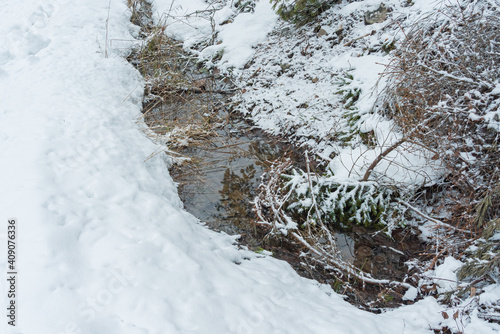 A not frozen stream in the snow. Close-up. Snowy winter concept