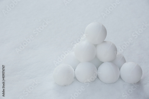 Pyramid of perfect snowballs on snow outdoors. Space for text