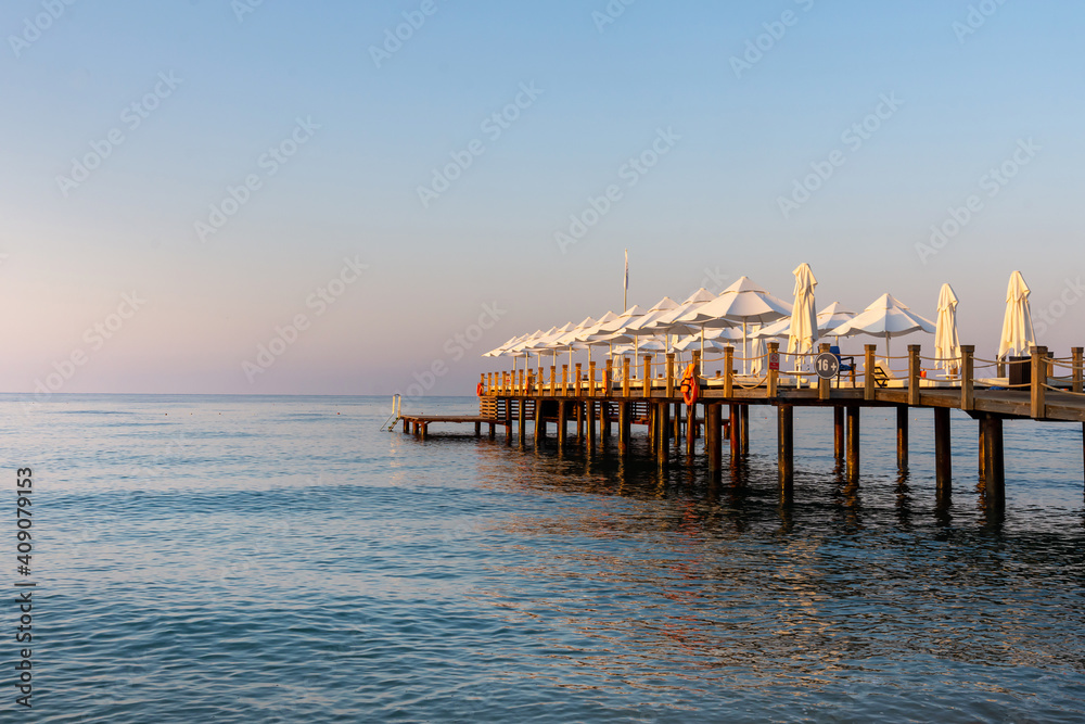 Fototapeta premium Pier with white umbrellas and sunbeds in luxury beach hotel in Antalya, Turkey