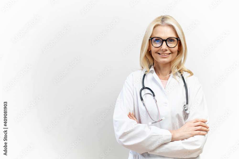 Smiling female doctor pediatric, physical, therapist wearing a white medical gown with a stethoscope on the shoulders stands with arms crossed isolated on white, copy space. Healthcare and medicine Smiling female doctor pediatric, physical, therapist wearing a white medical gown with a stethoscope on the shoulders stands with arms crossed isolated on white, copy space. Healthcare and medicine
