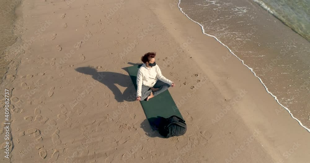 Mujer senior con mascarilla haciendo yoga en estera y dron orbitando