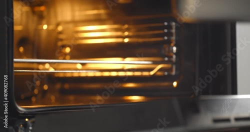 Close up of chef putting tray with meal in oven cooking dinner