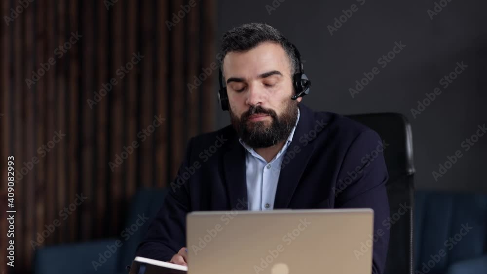 Handsome bearded man studying online using laptop web camera, writing lecture in notebook.Online education, remote working, home education.Online meeting, video call, video conference, courses online Handsome bearded man studying online using laptop web camera, writing lecture in notebook.Online education, remote working, home education.Online meeting, video call, video conference, courses online