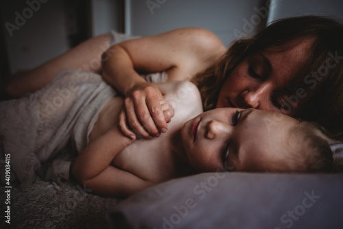 Mom hugging  and kissing her child in bed holding hands photo