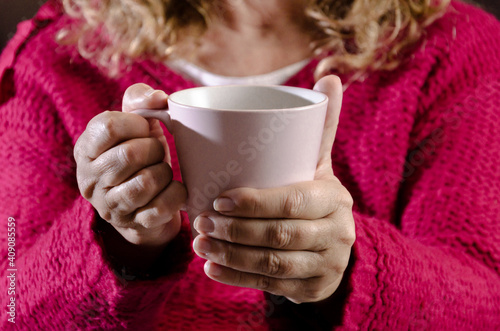 Adult woman with red sweater holding a cup of latte coffee