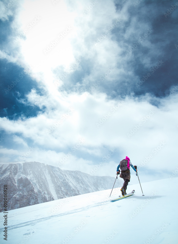 A skier tours up a snowy mountain in Colorado with blue skies A skier tours up a snowy mountain in Colorado with blue skies