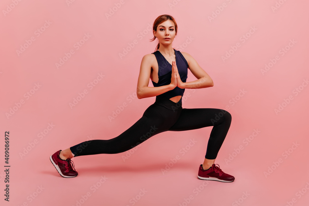 Sports girl join her hands in front of her breasts in gesture of gratitude. Fitness trainer posing, stretching legs