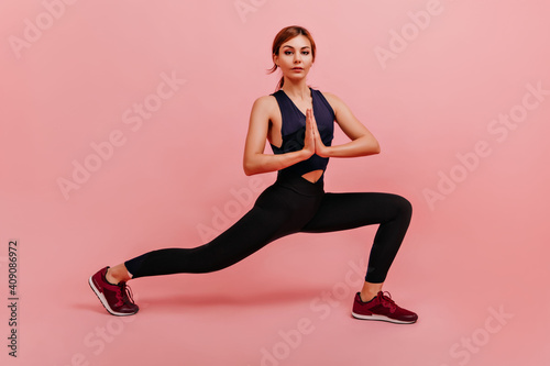 Sports girl join her hands in front of her breasts in gesture of gratitude. Fitness trainer posing, stretching legs © Look!