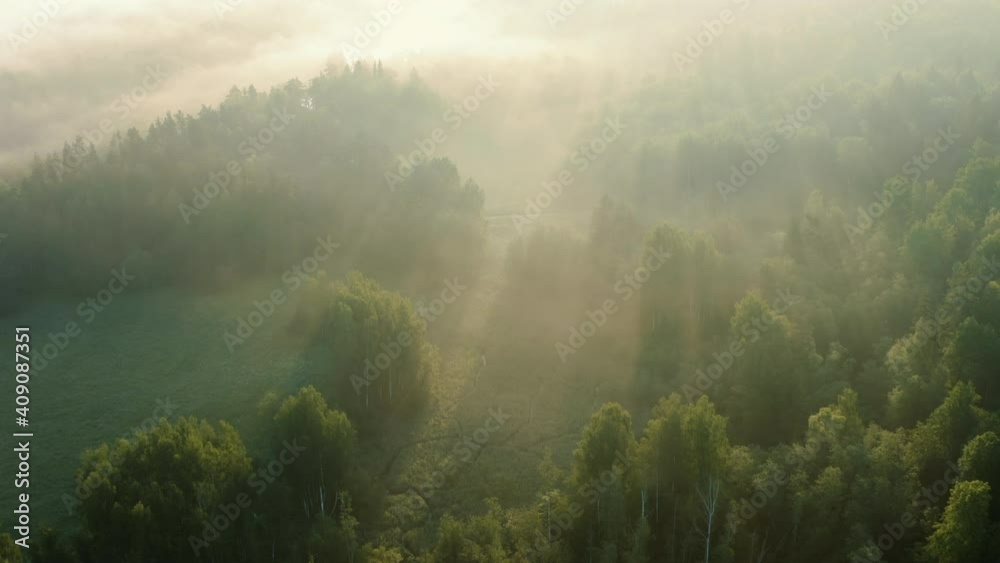 Aerial: amazing sunrise, sun rays through misty morning clouds over countryside
