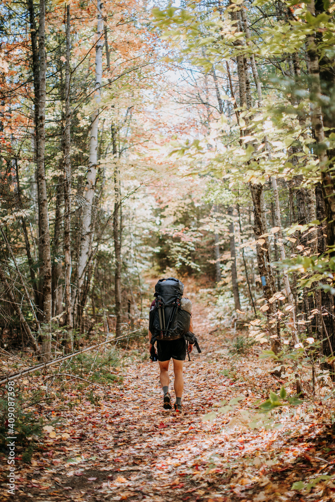 Man hikes with fully loaded pack down woodland trail in Maine Man hikes with fully loaded pack down woodland trail in Maine