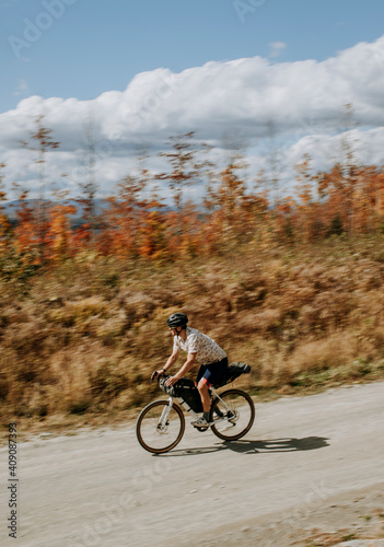 Man on bike speeds down gravel road in fall in Maine photo