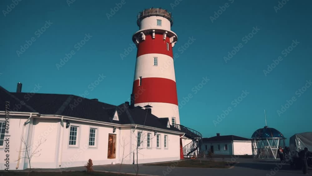 Beautiful bright lonely red and white lighthouse on hill on clear day close up Beautiful bright lonely red and white lighthouse on hill on clear day close up