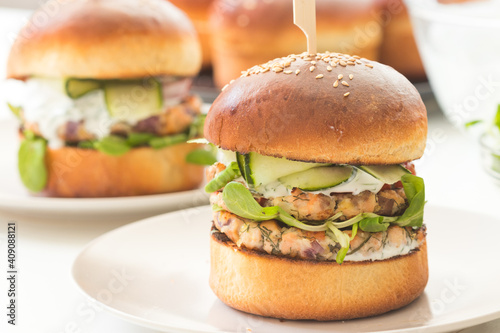 Homemade fish burgers with greens served for two on white plate