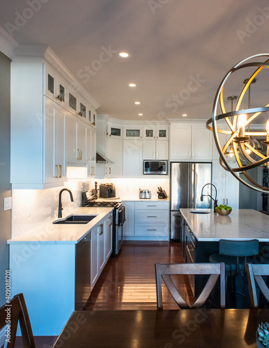 Modern kitchen with white cupboards, dark island and gold accents. photo