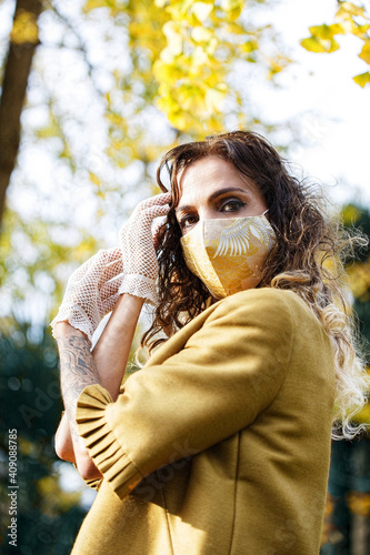 woman in yellow dress and mask in a park at autumn photo