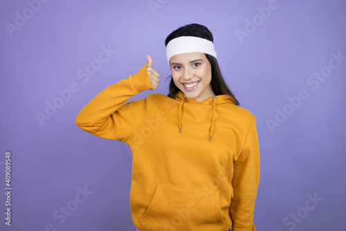 Wallpaper Mural Young latin woman wearing sportswear over purple background doing positive gesture with hand, thumbs up smiling and happy. cheerful expression and winner gesture. Torontodigital.ca