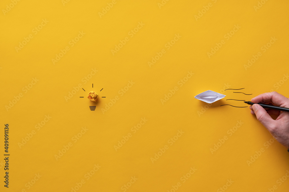 Paper made origami boat floating towards a light bulb Paper made origami boat floating towards a light bulb