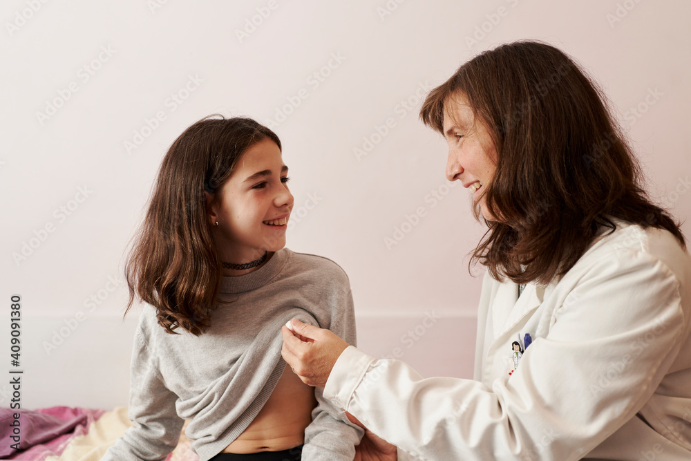 Female doctor teaching the temperature on a thermometer to a girl in her bed. Home doctor concept Female doctor teaching the temperature on a thermometer to a girl in her bed. Home doctor concept