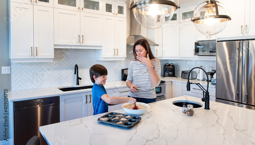 Mother and son making muffins together in a modern white kitchen. photo