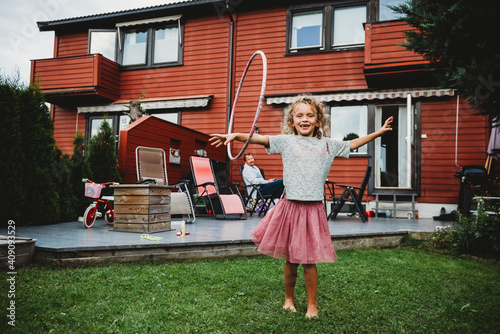 Cute girl in tutu playing with hula hoop in her backyard in Norway photo