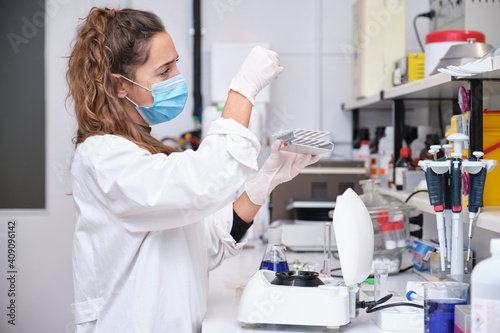 Young female scientist working in a laboratory sampling DNA in a test tube with a centrifuge. Laboratory research concept.