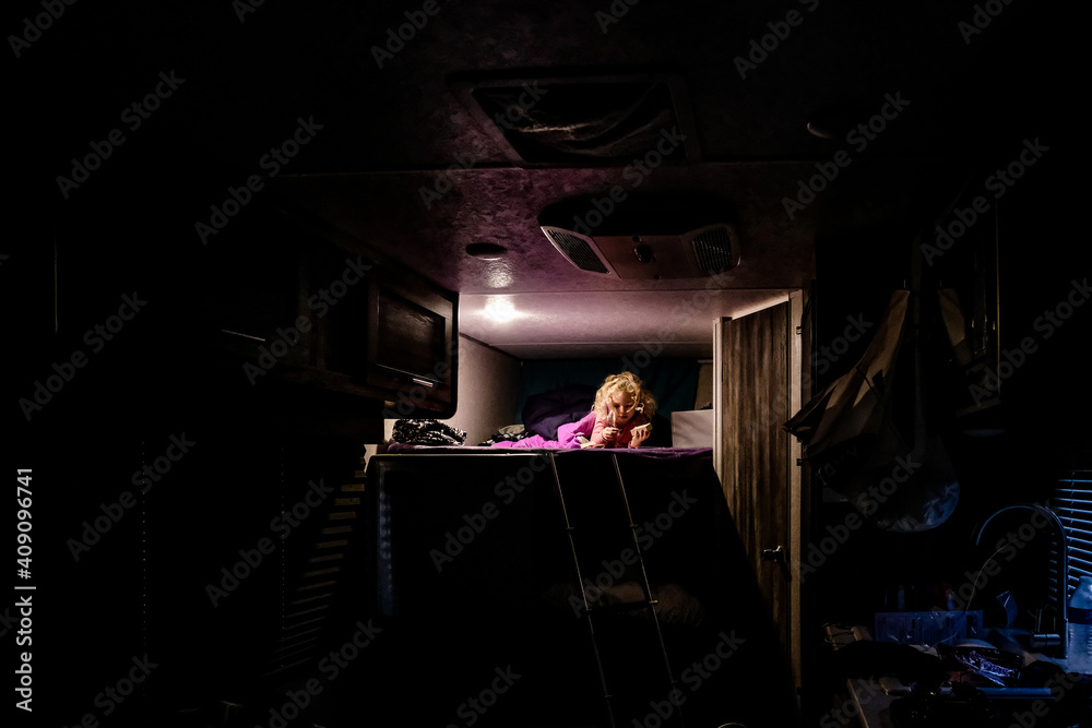 little girl laying on top bunk reading during a camping trip little girl laying on top bunk reading during a camping trip