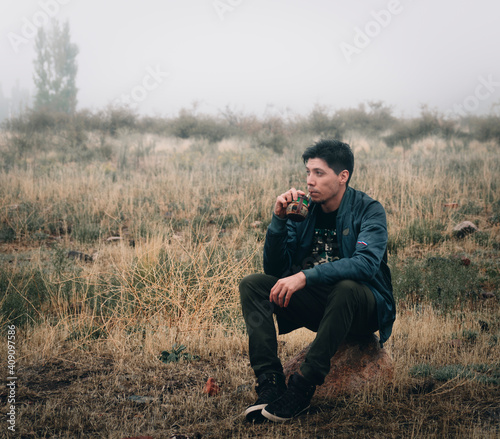 young man drinking mate in the field in the rain and with fog photo