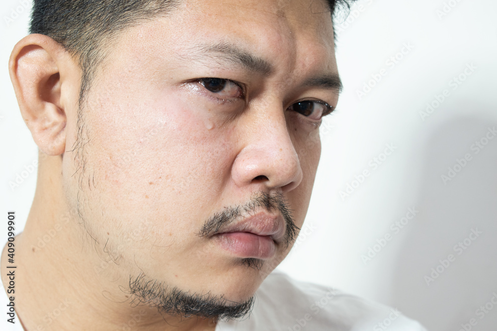 Obraz premium Portrait of unhappy and depressed man with black hair, feeling ashamed or sick, keeping eyes closed. Human face expressions and emotions concept. Isolated studio shot on gray background.