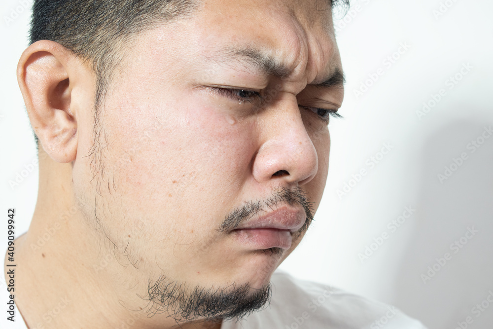 Portrait of unhappy and depressed man with black hair, feeling ashamed or sick, keeping eyes closed. Human face expressions and emotions concept. Isolated studio shot on gray background. Portrait of unhappy and depressed man with black hair, feeling ashamed or sick, keeping eyes closed. Human face expressions and emotions concept. Isolated studio shot on gray background.