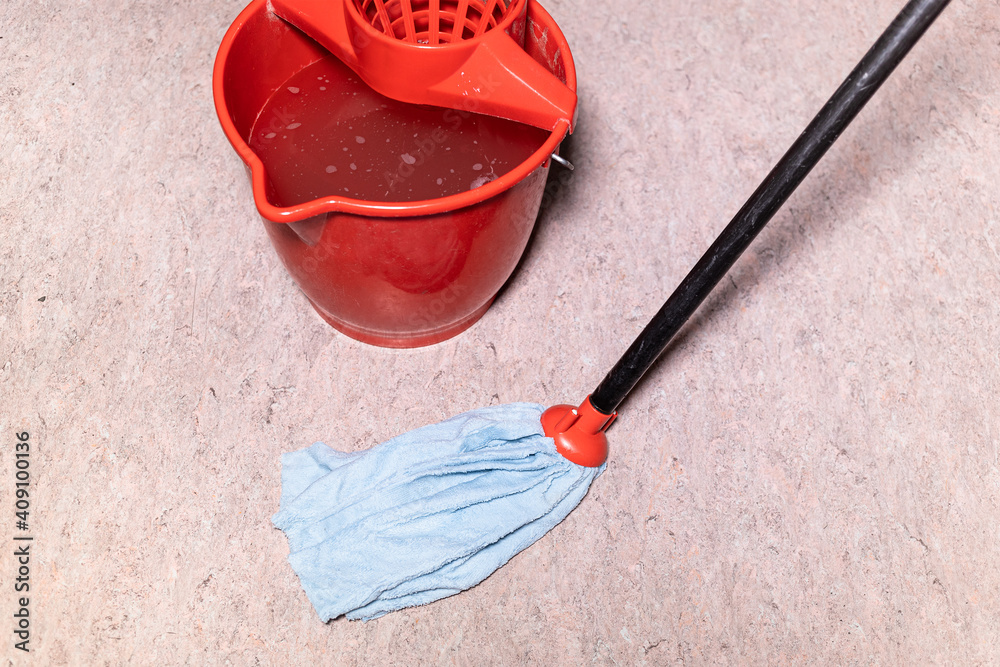mop cleans linoleum flooring near red bucket with water at home Stock
