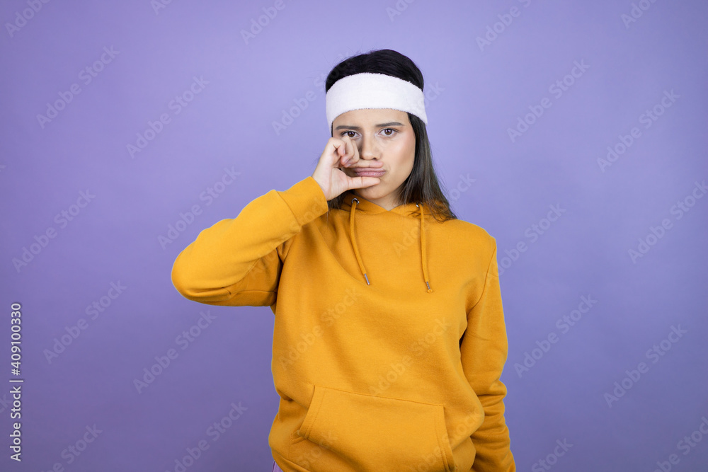Young latin woman wearing sportswear over purple background mouth and lips shut as zip with fingers. Secret and silent, taboo talking Young latin woman wearing sportswear over purple background mouth and lips shut as zip with fingers. Secret and silent, taboo talking