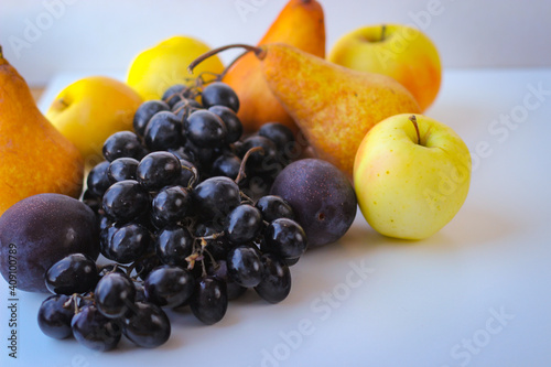 Ripe autumn fruits stand together creating a still life. Dark grapes  plums  pears and apples.