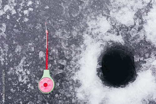 Winter fishing. Fishing rod for ice fishing. Tackle and ice hole. Background. Ice fishing concept