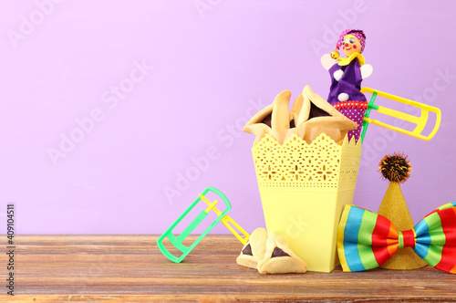 Purim celebration concept (jewish carnival holiday) over wooden table and purple background