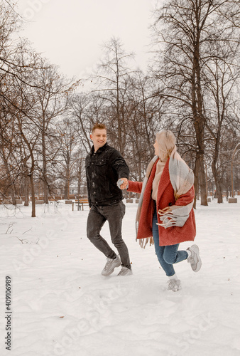 Young romantic couple is having fun outdoors in winter. Two lovers are hugging and kissing in Saint Valentine's Day. Hipster couple hugging each other in winter forest. Love story.