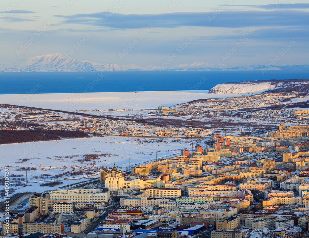 Top view of the city of Magadan. Beautiful evening cityscape. Magadan is located on the coast of the Sea of ​​Okhotsk. Sea bay and mountains in the distance. Magadan Region, Far East Russia. Siberia.