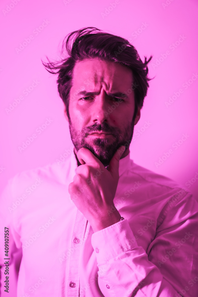 Studio lifestyle, portrait of a serious Caucasian young man in a white shirt, illuminated with a pink neon light Studio lifestyle, portrait of a serious Caucasian young man in a white shirt, illuminated with a pink neon light