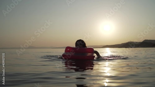 Middle shot of girl lying and swimming on the inflatable mattress in the evening sea. Woman lying and swimming on the inflatable mattress in the sea. Khalkidhiki, Greece High quality FullHD footage