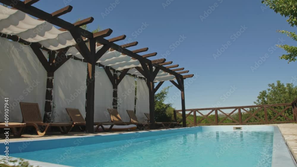 Open-air pool with clear blue water on the background of a mountain-forest landscape and the endless sky. Camera Movement Above Water To The Side Of The Mountains. Open-air pool with clear blue water on the background of a mountain-forest landscape and the endless sky. Camera Movement Above Water To The Side Of The Mountains.