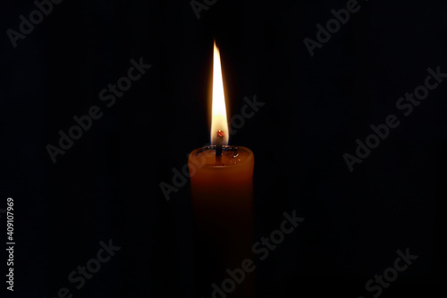 closeup of an isolated flame of a burning wax candle in the dark, black background