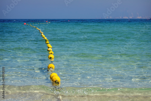 Seascape with floating buoys and rope dividing area on beach. Blue water on sea shore of Al Mamzar Beach Dubai