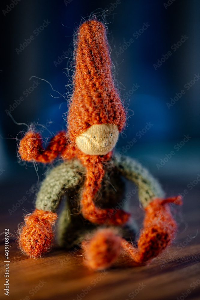 Fototapeta premium Handmade crochet autumn Gnome, with red hat and scarf, sitting position.