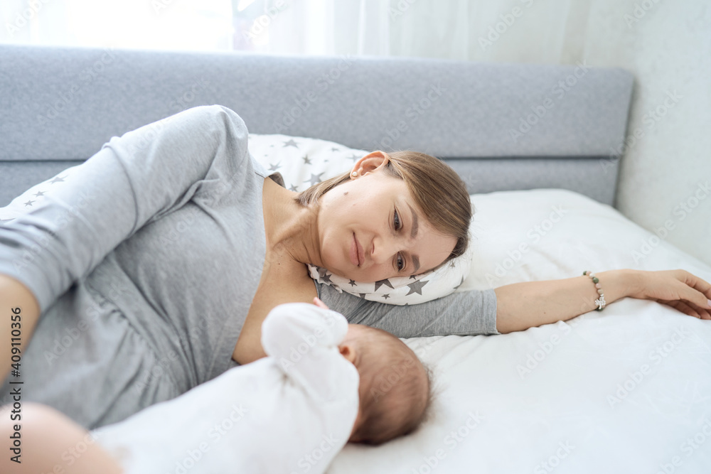 Beautiful woman breastfeeding her baby in a cozy house on the bed. High quality photo