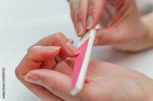 Woman doing manicure with nail file. Home nail care concept photo