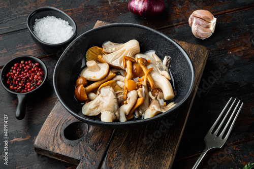 Marinated mushrooms, on old dark wooden table background