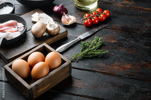 Healthy breakfast ingredients for fried eggs, on old dark  wooden table background , with space for text  copyspace