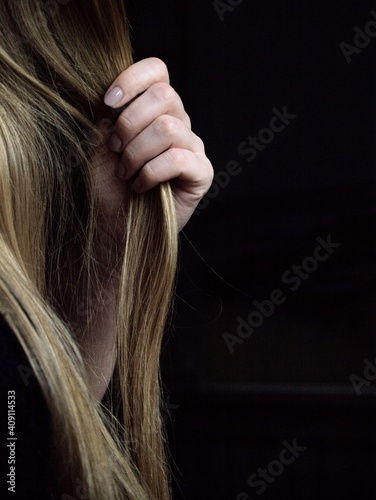 Hands playing with hair on a black background.