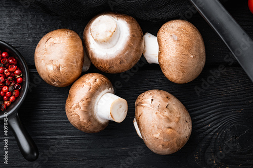 Raw mushrooms champignons, on black wooden table background, top view flat lay