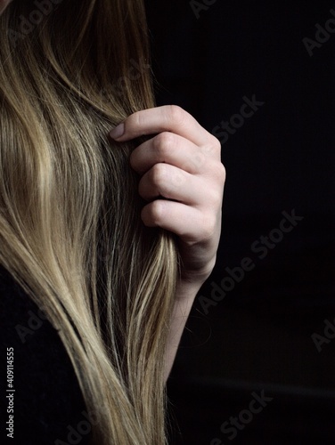 Hands playing with hair on a black background.