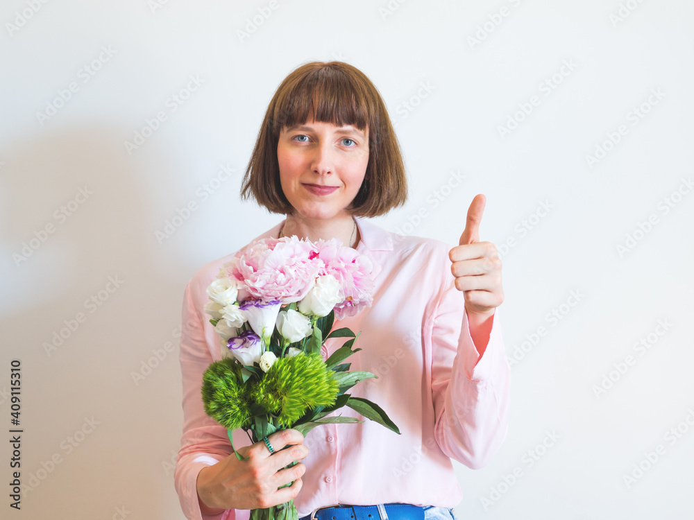 Young woman holding beautiful bouquet with hand thumbs up on light gray background Young woman holding beautiful bouquet with hand thumbs up on light gray background